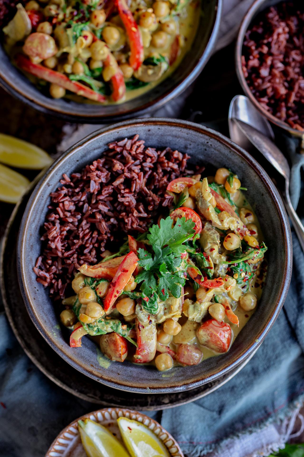 Pilz-Kichererbsen-Kokoscurry mit Spinat und Kirschtomaten in tiefem Topf.