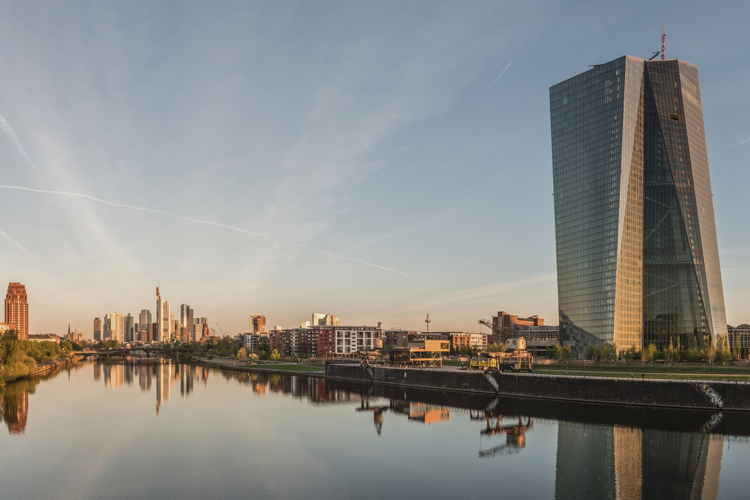 A financial capital's skyline at dawn: twin towers beyond a low river grid, the sort of administrative morning in which every corridor begins to ask for papers.